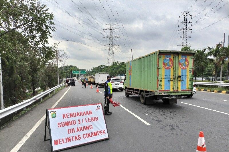 Petugas melakukan pengaturan lalu lintas dekat papan pengumuman bertuliskan kendaraan sumbu tiga atau lebih dilarang melintas Cikampek di Interchange Cawang, Jakarta